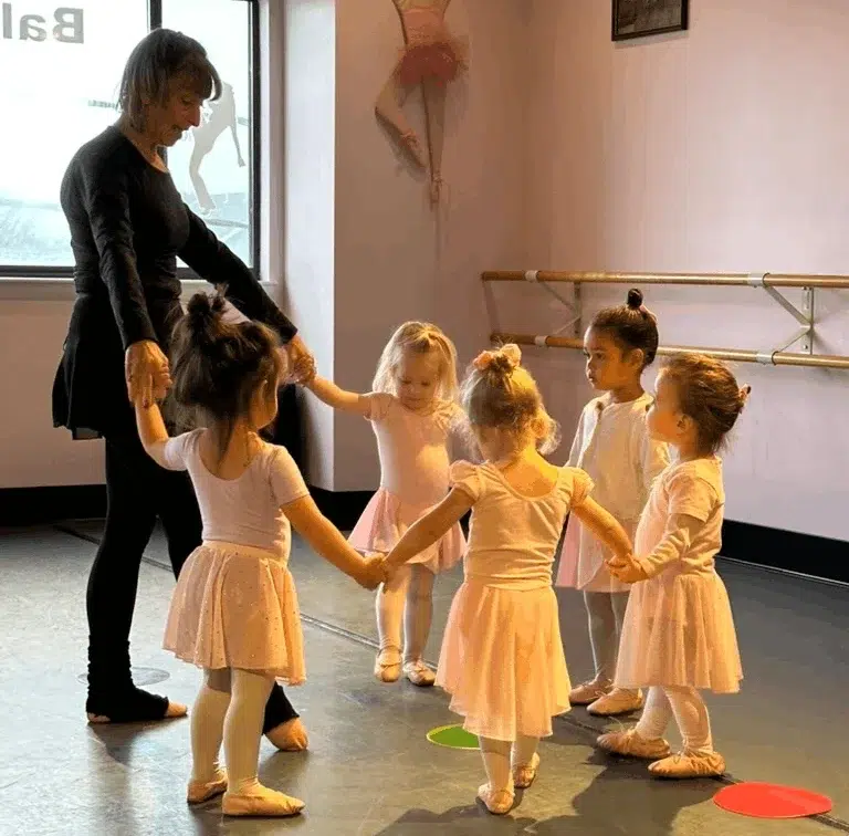 Ballet Instructor Leading Young Dancers In Studio Circle