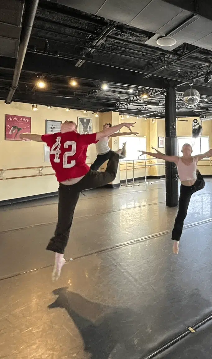 Contemporary Dancers In Mid-Air Leap At Studio