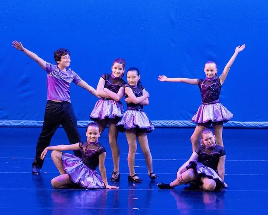 Tap - A Group Of Six Young Dancers Posing On Stage In Purple And Black Costumes. - ATJ
