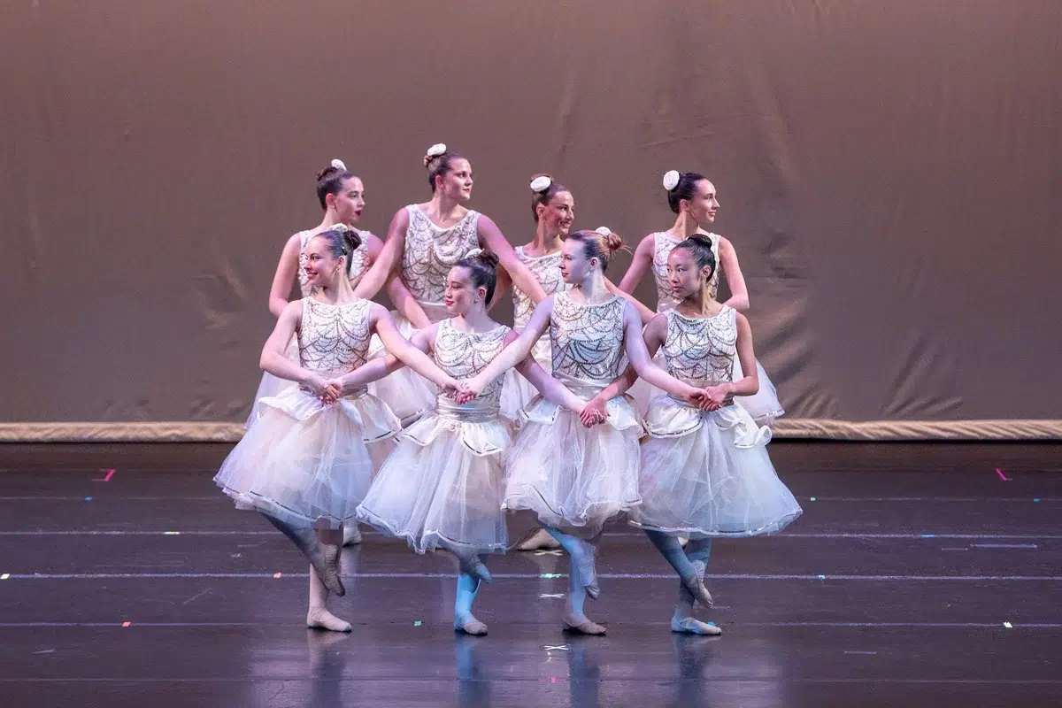 Ballet dancers in white classical tutus joined together on stage