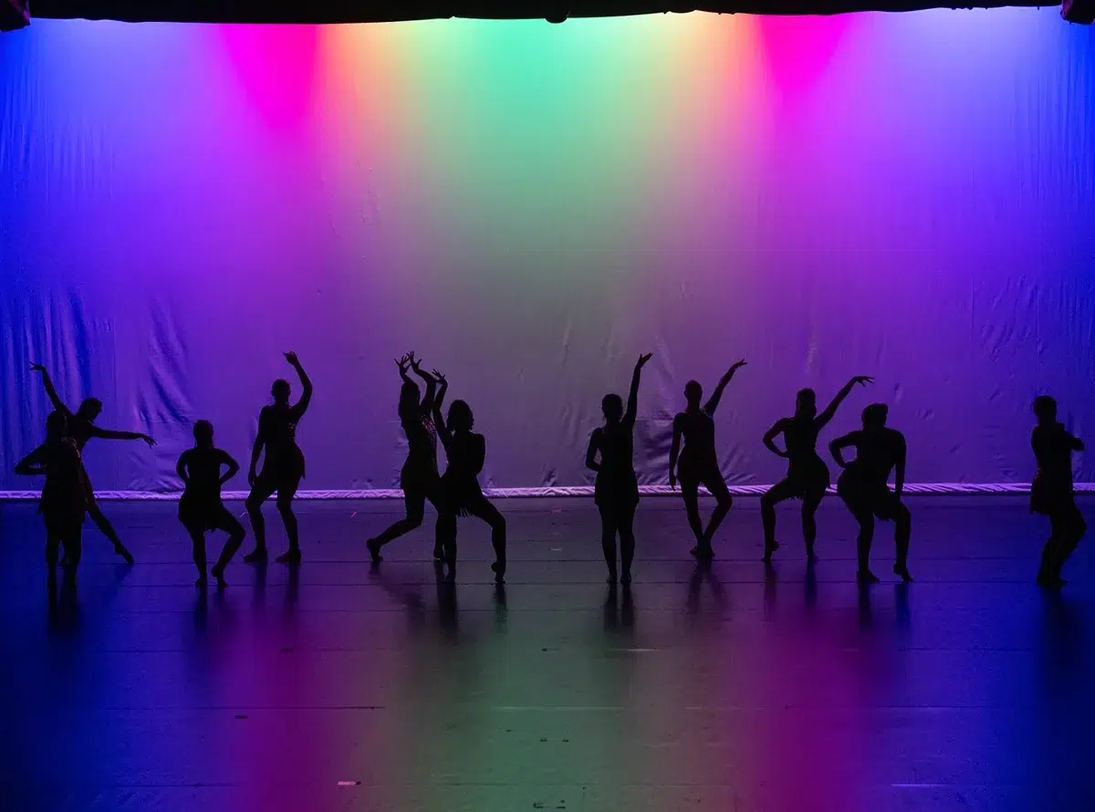 Jazz Fusion dancers in silhouette against a rainbow-lit backdrop