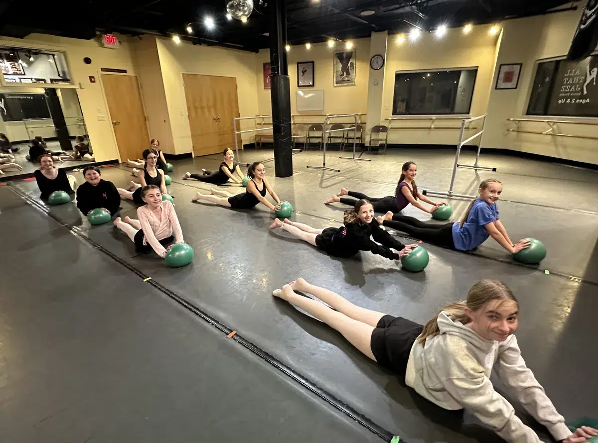 Pre-Pointe dancers stretch on the studio floor using conditioning balls