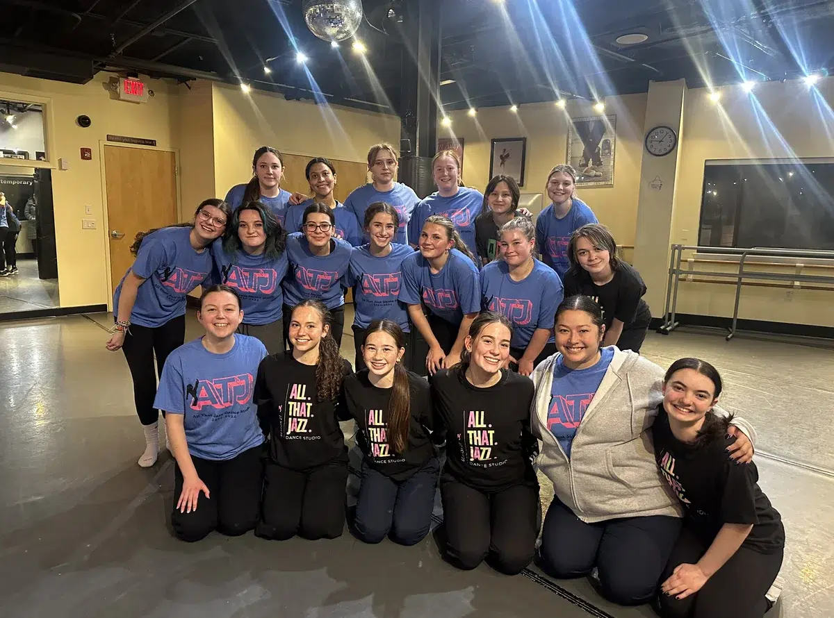 High school dancers gather together in All That Jazz shirts in the studio