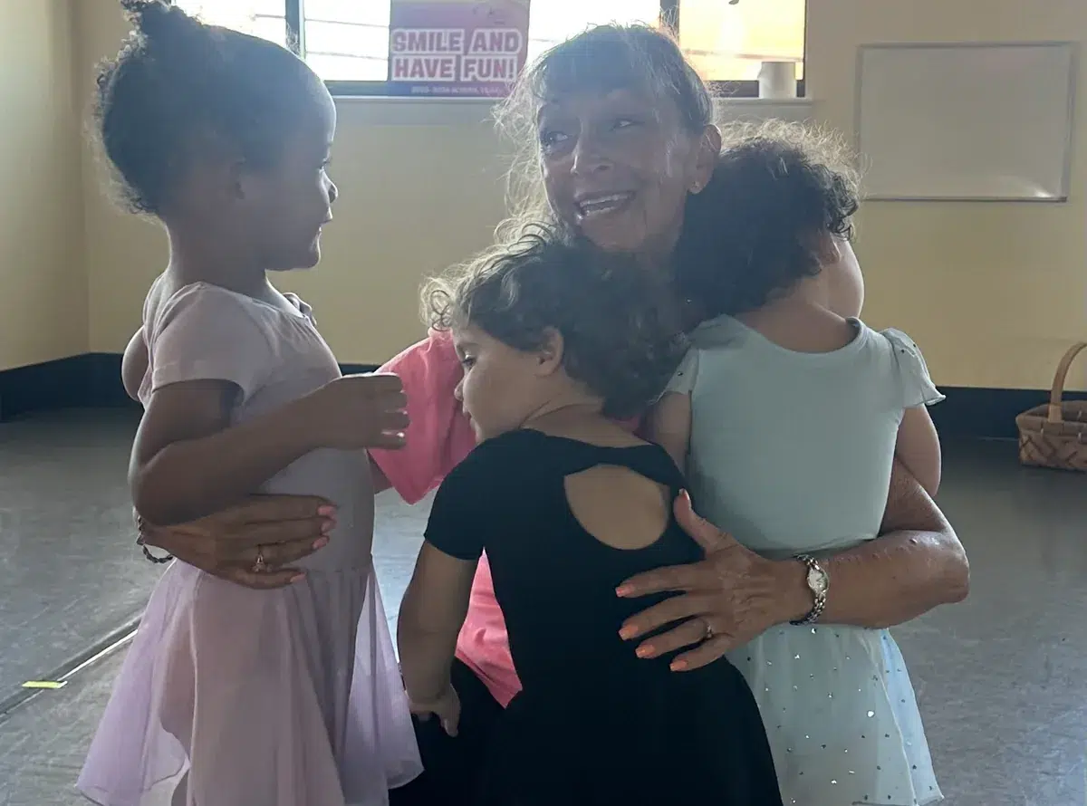 A teacher hugging three toddler ballerinas during a Twirling Tykes class at All That Jazz Dance Studio